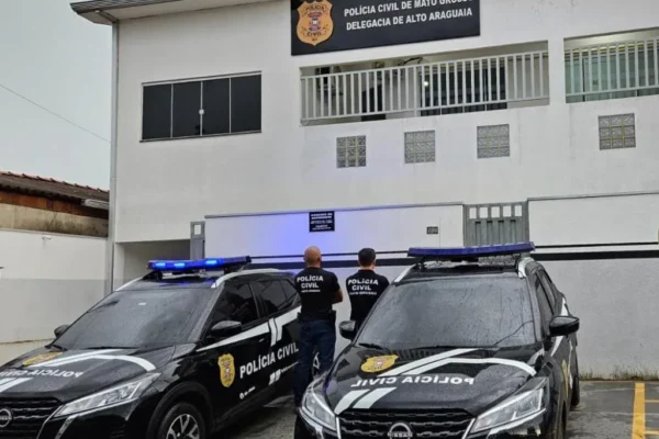 Policiais Civis ao lado de viatura em frente à delegacia